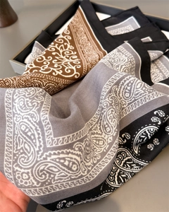 Detailed close-up of paisley pattern silk scarf showing luxury texture and brown grey tones