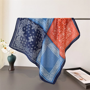 Detail of paisley print silk scarf showing vibrant colors and elegant drape on a metal stand