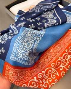 Close-up of silk-feel scarf with navy blue and orange paisley floral print detail