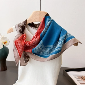 Detail of colorful Paisley pattern silk scarf tied on a white knit tank top
