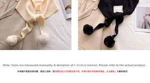 Détails de la maille épaisse et des pompons doux en coloris blanc cassé et noir classique