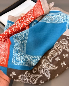 Macro shot of paisley pattern silk scarf with vibrant orange, blue and brown color segments