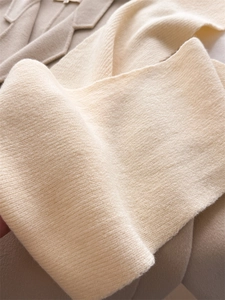 Détail macro de la texture en maille côtelée et du tissu premium de l'écharpe d'hiver beige