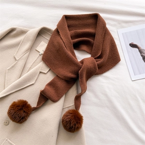 Tour de cou en tricot marron avec pompons en peluche sur un manteau pour chaleur hivernale