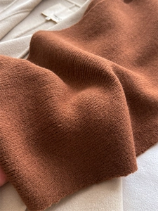 Gros plan détaillé sur la texture de l'écharpe en maille côtelée brune avec étiquette