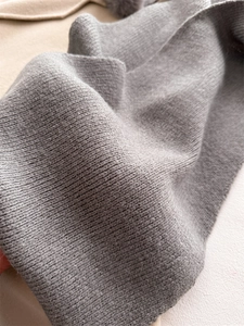 Gros plan sur la texture du tricot gris doux et les détails de tissage d'une écharpe