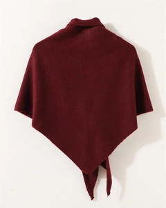 Detalle del poncho de punto burdeos con cuello alto y dobladillo en punta de textura gruesa