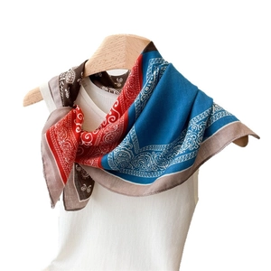 Classic paisley print square scarf tied on a white vest with rich blue and red patterns