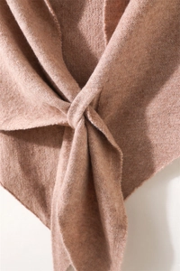 Detalle de chal de punto en color rosa empolvado con un diseño único de nudo cruzado