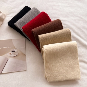 Flat lay of soft knitted scarves in six autumn colors with cozy textured material