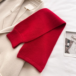 Detailed close-up of a red chunky knit scarf texture on a cream winter coat