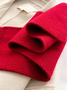 Detailed macro view of the thick red knit scarf with chunky texture and soft warm fibers