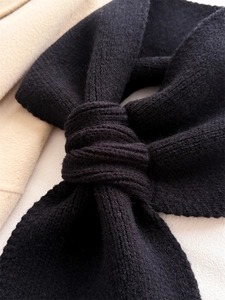 Detailed view of black knitted scarf with vertical stripes showing cross-knot texture