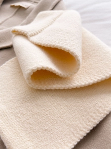 Close-up of thick creamy knit texture and ribbed edge detail on warm winter scarf