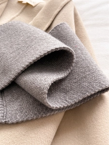 Macro shot of dark grey knit fabric texture paired with a camel wool coat surface