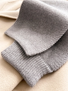 Macro view of grey knitted scarf showing ribbed edge details and soft wool texture