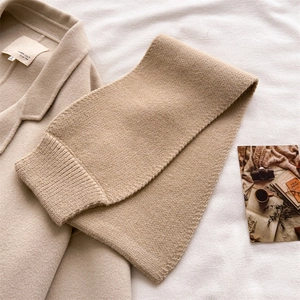 Close-up of thick beige ribbed knit scarf texture on a wool coat for winter fashion