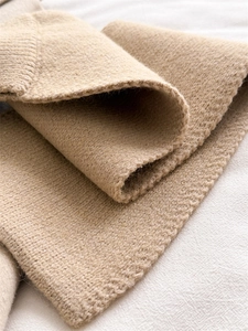 Close-up of camel knit scarf showing soft cashmere wool texture and thickness