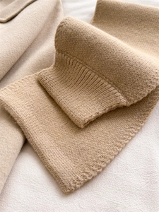 Detail view of camel knit scarf showing soft ribbed texture and winter neck warmer fabric