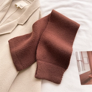 Close-up of caramel knit scarf with ribbed texture on an elegant beige wool coat