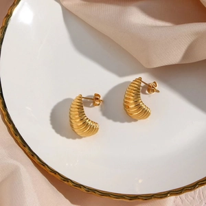 Dettaglio orecchini a goccia placcati oro 18K con texture a coste su tessuto di seta