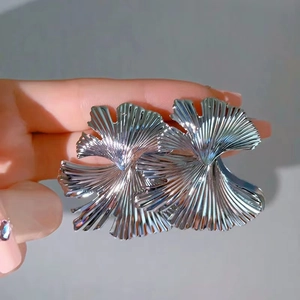 Detailed close-up of silver ginkgo leaf earrings showing intricate textured metallic folds