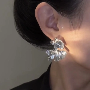 Detailed close-up of silver ginkgo leaf earrings with a brushed metal finish on model