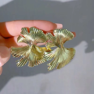Detailed view of large golden ginkgo leaf earrings with radial vein texture finish