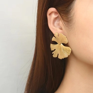 Chic 18K gold plated ginkgo leaf stud earrings shown on model with brushed texture