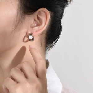 Polished silver wide C-shape hoop earrings worn by a model in a minimalist style