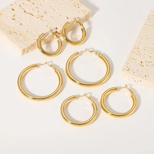 Three sizes of 18K gold plated thick hoop earrings displayed on elegant stone blocks