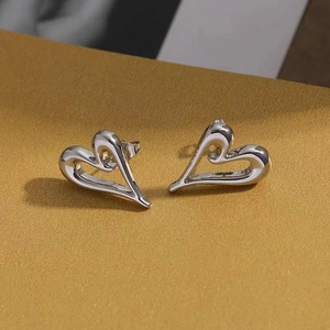 Irregular hollow heart stud earrings in polished silver finish on a golden textured base
