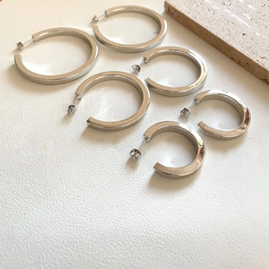 Detailed view of three pairs of silver C-shaped hoop earrings in graduated sizes