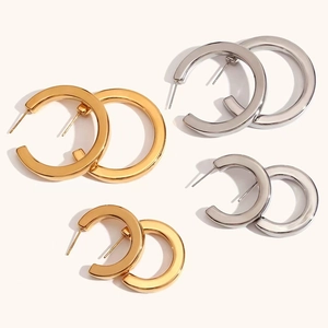 Detailed view of C-shaped chunky hoop earrings in gold and silver polished metal finishes