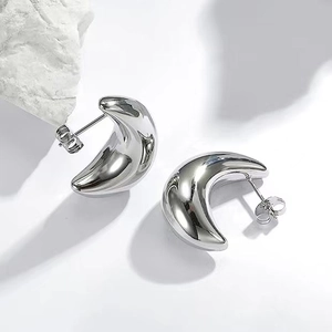 Polished silver hollow crescent moon drop earrings with minimalist C-shape design on white rock