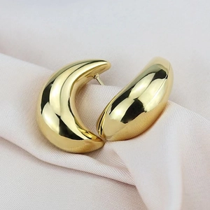 Minimalist golden hollow crescent earrings with a polished mirror finish on silk fabric