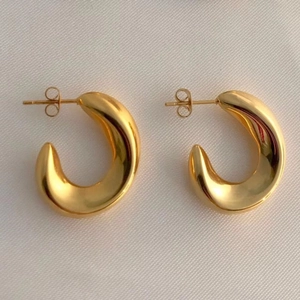 Close-up of chunky gold-plated C-shape hoop earrings with high polish finish