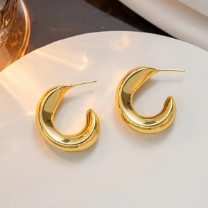Detailed view of chunky gold-plated C-shaped hoop earrings with a high-polished finish