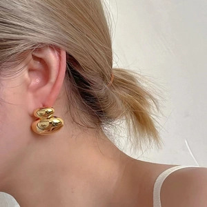 Polished 18K gold-plated double-layered pebble earrings worn on a female model