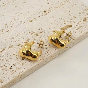 Detailed macro shot of irregular lava texture on 18K gold plated earrings on a stone base