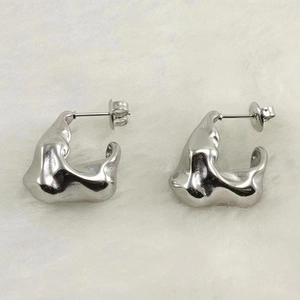 Irregular fluid silver earrings in liquid metal style on white faux fur background