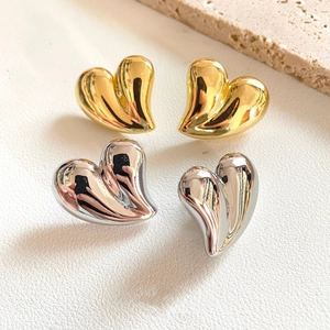 Macro detail of high-polish heart stud earrings in gold and silver finishes