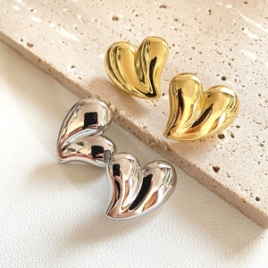 Macro shot of 18K gold and silver plated chunky heart earrings on textured stone