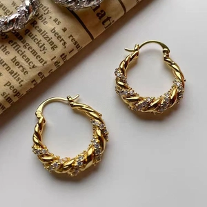 Elegant gold twisted rope hoop earrings with pavé zircon stones on white background