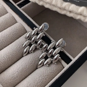 Macro shot of silver multi-layered olive-shaped metal stud earrings on velvet