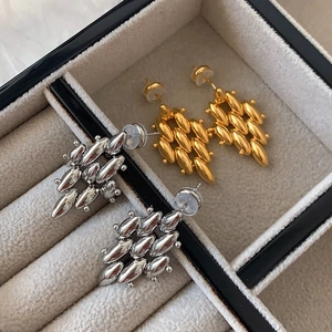 Detail of 18K gold and silver plated woven bead earrings in a gray jewelry box