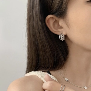 Boucles d'oreilles créoles géométriques en C torsadées argentées portées par un mannequin
