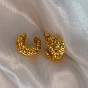 Boucles d'oreilles créoles croissant dorées avec texture torsadée sur soie blanche