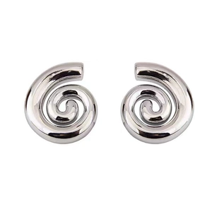 Détail macro de boucles d'oreilles spirales argentées avec fini poli et texture épaisse