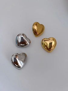 Detail of heart-shaped metal earrings with high-shine gold and silver mirror finish